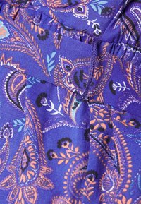 Tecido roxo com um padrão paisley em laranja, preto e azul. Textura suave com detalhes de cintura franzida e elementos de design intrincados.