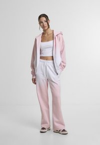 Light pink hoodie with white accents, paired with matching sweatpants featuring an ombre effect. Casual fit with elastic waistband.