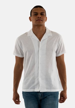 Camisa blanca de manga corta hecha de una tela ligera y texturizada, con cuello de pico y cinco botones brillantes en la parte delantera.