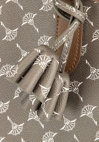 Szara skórzana torba z teksturowaną powierzchnią, wzorzystym designem z białymi akcentami oraz szczegółowym frędzlem przymocowanym do paska.