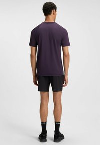 Purple short-sleeve athletic shirt with raglan sleeves, paired with black shorts. Textured fabric and subtle stitching details.