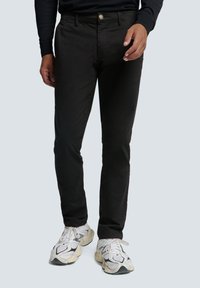 Zwarte recht gesneden broek van katoen met een knoopsluiting, met een gladde textuur en een licht tapered ontwerp, gecombineerd met witte sneakers.