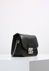 Svart texturerad handväska med klaffdesign, silverdetaljer och kedjerem. Har en clasp-stängning och en strukturerad siluett.