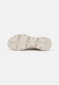 Suola di una sneaker, caratterizzata da un materiale in gomma bianca texturizzata con un motivo di scanalature e perni per trazione e durabilità.