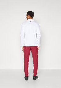 Balta krekla ar garām piedurknēm un apkakli, kopā ar sarkaniem biksēm ar baltām sānu svītrām; melnas kurpes papildina tērpu.