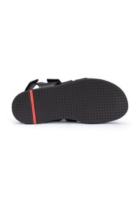 Sandalo nero con cinturini regolabili, suola in gomma testurizzata e un accento rosso a contrasto sul tallone. Chiusure in velcro per una vestibilità sicura.