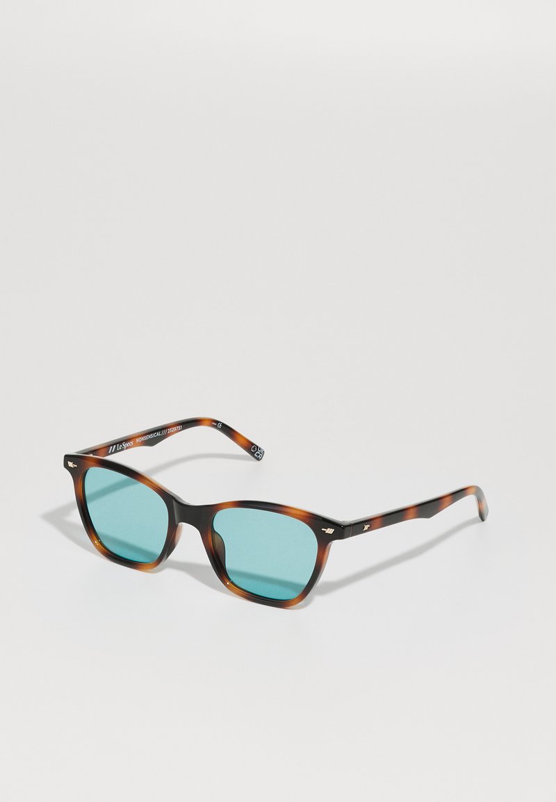 Occhiali da sole tartarugati con lenti azzurrate, forma quadrata e sottili aste nere con dettagli dorati e branding sulla tempia.