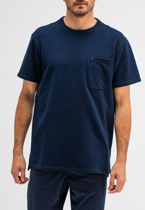 Marineblaues Baumwoll-T-Shirt mit kurzen Ärmeln, rundem Ausschnitt und einer Brusttasche. Strukturierter Stoff und seitliche Schlitze am Saum.