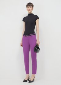 Black fitted top, vibrant purple tailored pants, black belt, and shiny black handbag. Slim silhouette with pointed black heels.