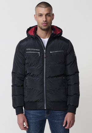 Chaqueta de plumas negra con capucha, con forro rojo, bolsillos con cremallera y puños acanalados. Fabricada con material suave e insulated.