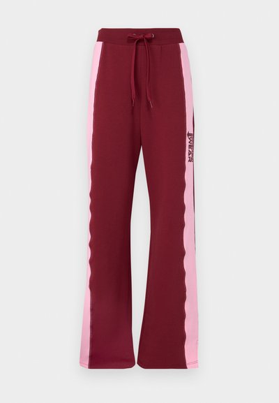Bordeaux joggebukser med vide ben, med rosa sidestriper og strikket liv. Inkluderer en logo-trykk på venstre ben.