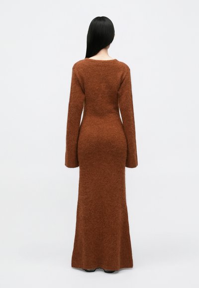 Dolga rjava pletena obleka z текстurirano, puhasto površino, oprijetim silhueto, dolgimi rokavi in okroglo ovratnikom, prikazana s hrbtne strani.