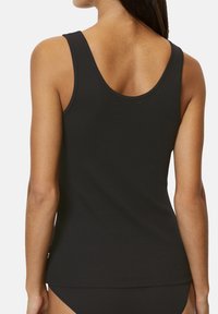 Schwarzes Tanktop mit gerippter Textur, tailliertem Schnitt und Rundrücken. Der Stoff ist weich und hat minimale Akzente. Ideal zum Schichten.