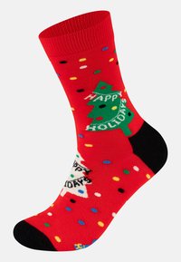 Červené ponožky se skvělými puntíky a veselými vzory, včetně zeleného vánočního stromečku a textu "Šťastné svátky". Černé akcenty na patě a prstech.