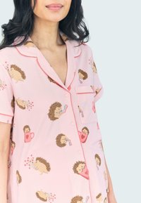 Camisa de pijama rosa de manga corta con un patrón de erizos, cuello ribeteado, bolsillo e ilustraciones divertidas de erizos.