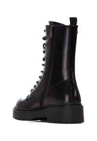 Botas de combate de cuero negro con cremallera lateral, parte delantera con cordones, suela gruesa y un acabado suave y brillante. Costuras y ojales detallados.