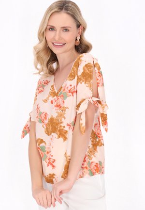 Blusa floreale in morbido tessuto pesca, con scollatura a V, maniche corte con dettagli a fiocco e un motivo di fiori arancioni e rosa.