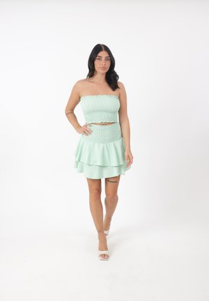 Conjunto de dos piezas en un suave verde menta. La parte superior es un diseño sin tirantes con fruncidos; la falda cuenta con volantes en capas con una textura similar.