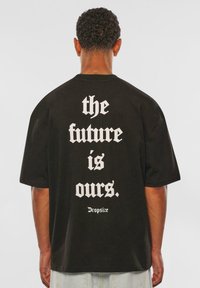 Black cotton t-shirt featuring bold white text on the back that reads “the future is ours.” and “Dropsize.” Loose fit with short sleeves.