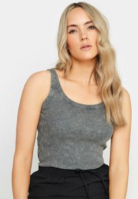 Grå ribbad tanktopp med breda axelband och rundad halsringning, tillverkad av en lätt, texturerad tyg. Enfärgad utan ytterligare mönster eller detaljer.