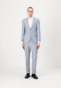 Traje azul claro hecho de una tela suave, con un diseño de un solo botón, solapas de muesca y zapatos negros. Ajuste limpio y entallado.