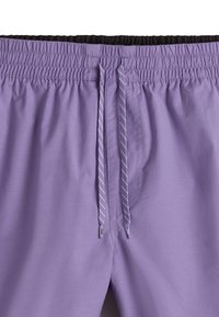 Shorts de bain violets avec une taille élastique, dotés d'une doublure intérieure noire et d'un cordon de serrage avec des rayures grises. Texture lisse.