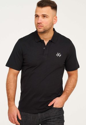 Schwarzes Polohemd aus weichem Material, mit Knopfleiste und kleinem weißen Logo auf der linken Brust. Kurze Ärmel und lockere Passform.