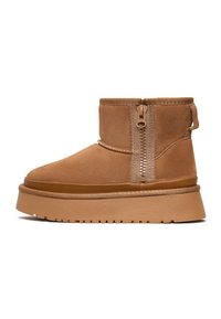 Braune Wildleder-Stiefeletten mit seitlichem Reißverschluss, runder Spitze und dicker Sohle. Strukturierte Oberfläche mit einem glatten Akzent am Sohlenrand.