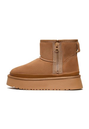 Stivaletti in suede marrone con cerniera laterale, punta tondeggiante e suola spessa. Finitura testurizzata con un accento liscio attorno al bordo della suola.