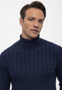Marineblaue Strickpullover mit Rollkragen und geripptem Muster. Verfügt über einen hohen Kragen und eine figurnahe Silhouette.