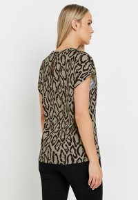 Kurzarm-Oberteil in Olivgrün mit schwarzem Leopardenmuster, verfügt über ein Keyhole-Rückendetail und eine weiche Stofftextur.
