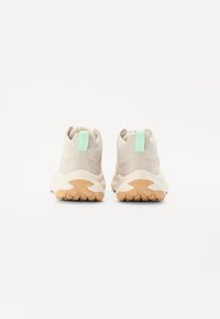 Beige treningssko med overdel i mesh og gummi, med en mintgrønn hælsløyfe og teksturert gummisåle for godt grep.