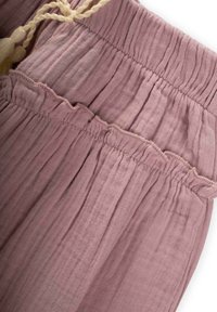 Helles Pink, strukturierter Stoff mit gerafftem Taillenbund, abgeschlossen mit dezenten Rüscheln und einer geflochtenen Kordel zur Anpassung.