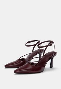 Chaussures à talons hauts en cuir bourgogne avec un bout pointu, une lanière de cheville et un design entrecroisé. Talon fin et texture lisse.