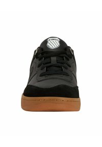 Svart atletisk sneakers med läder- och mockamaterial, med rund tå, svarta snören, gummisula och en logotyp på tungan.