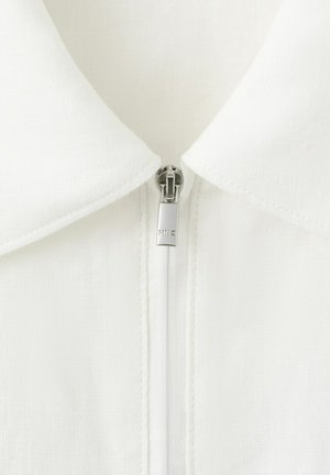 Biały materiałowy kołnierz z srebrnym suwakiem z wygrawerowanym napisem "MNG", umieszczony centralnie i zasunięty aż pod sam koniec kołnierza.