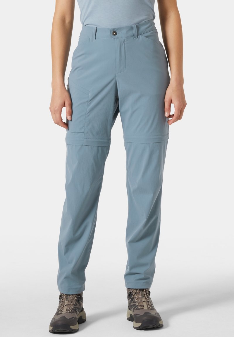 Vaaleansiniset retkeilyhousut, joissa on kevyestä kankaasta valmistetut vetoketjulliset lahkeet, sivutaskut, nappisuljin ja väljähkö istuvuus.