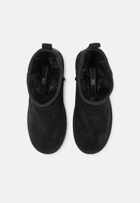 Botas de tobillo negras de ante con un interior suave y peludo. Cuentan con una puntera redondeada y paneles laterales elásticos para un fácil uso.