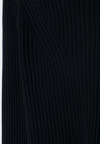 Tissu tricoté noir à côtes avec des lignes verticales, présentant une surface texturée et des détails de couture en diagonale pour un intérêt visuel.