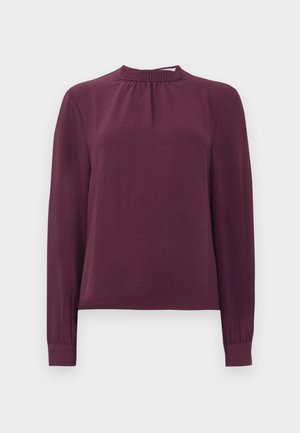 Langärmlige Bluse in Pflaumenfarbe mit gerafftem Mock-Neck und Bündchen, aus strukturiertem, leichtem Stoff, vor einem schlichten weißen Hintergrund präsentiert.