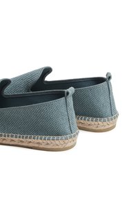 Textiele instap schoenen in een gedempt blauw-grijze kleur. Kenmerken zijn een geweven textuur, ronde randen en jute touwdetails rond de zool.
