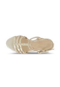 Sandalia de tacón alto con tiras en dorado metálico con un acabado suave, que presenta tachuelas en forma de pirámide, puntera abierta y correa de tobillo ajustable.