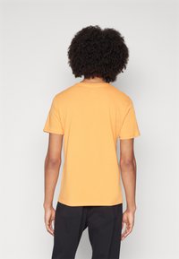 Kortærmet, orange T-shirt lavet af blødt stof med rund halsudskæring og en afslappet pasform, med en glat tekstur og uden synlige mønstre.