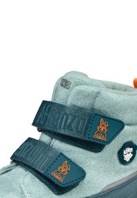 Lichtblauwe stoffen laars met donkerblauwe klittenbandsluiting, oranje accent en rubberen zool; heeft een kattenlogo op de band.