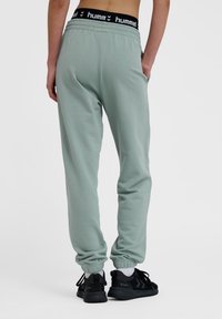 Hummel grüne Jogginghosen mit elastischem Bund und gerippten Knöcheln. Hergestellt aus weichem Stoff, mit seitlichen Taschen und einem schwarzen Logo-Akzent.