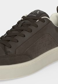 Baskets en cuir marron foncé avec lacets assortis, semelle blanche et logo Armani Exchange sur la languette et le panneau latéral.