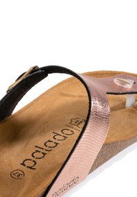 Svart sandal med ett metalliskt roseguldrem, texturerad yta, korkfotbädd och beige foder. Har ett guldfärgat spänne och logo.