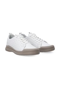 Hvide sneakers med et struktureret mønster, snørebåndsdesign og en tan gummisål med en let hævet hæl.