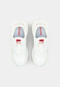 White sneakers with a smooth leather and mesh upper, featuring red accents on the tongue and side, and a cushioned sole for comfort.