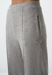 Grijze, geweven loungebroek met een ontspannen pasvorm, voorzien van zijzakken en een brede tailleband, gemaakt van een zachte, gebreide stof.